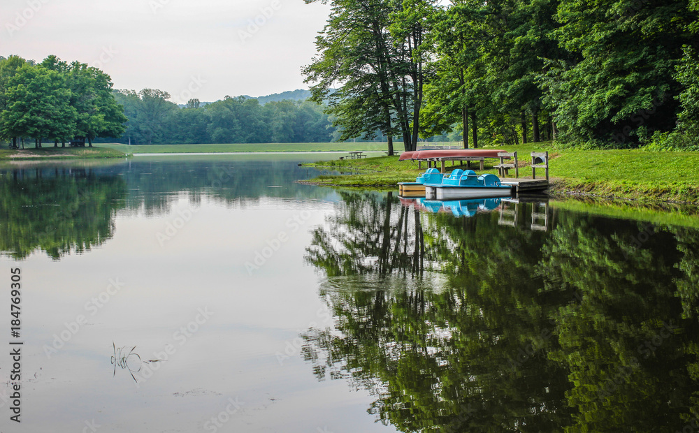 Naklejka premium Summer Day At The Lake. Paddleboats and canoes line the shore of the lake at Scioto State Park in Chillicothe, Ohio