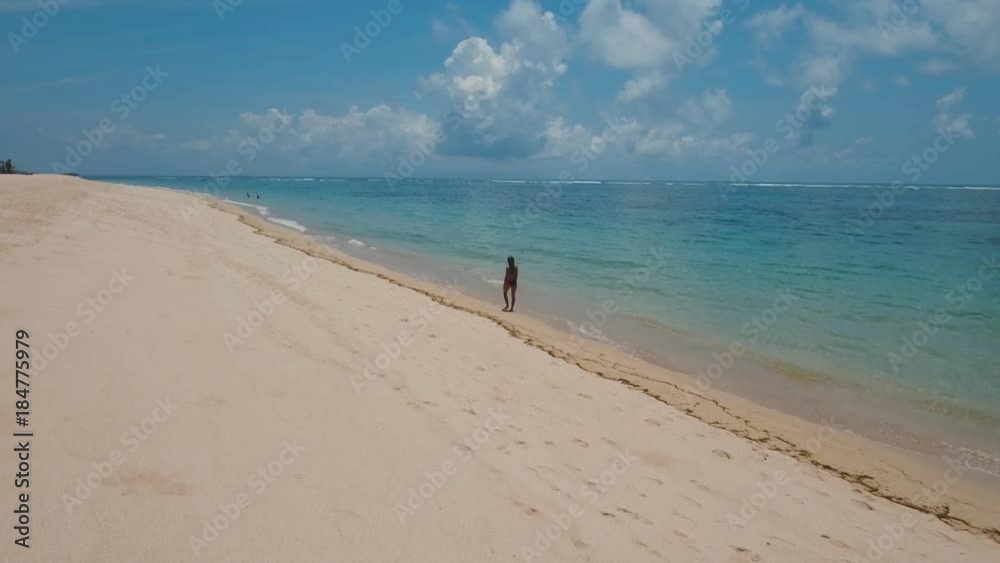 Young girl in a swimsuit walking on the beach. Aerial view of on tropical beach Bali,Indonesia. Travel concept, Aerial footage, 4K video. Young girl in a swimsuit walking on the beach. Aerial view of on tropical beach Bali,Indonesia. Travel concept, Aerial footage, 4K video.