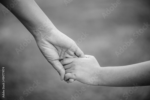 Black and white of mother holding a hand of his son.  Love , famiy and mother day concept.
