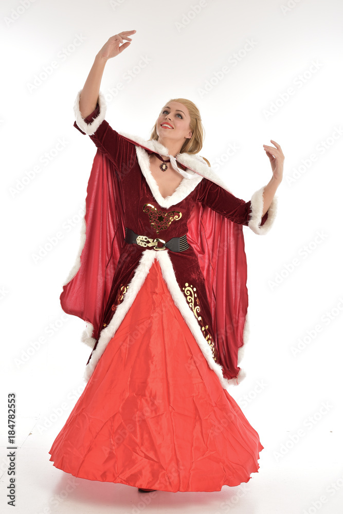 full length portrait of pretty blonde lady wearing red and white christmas inspired costume gown, standing pose on white background.