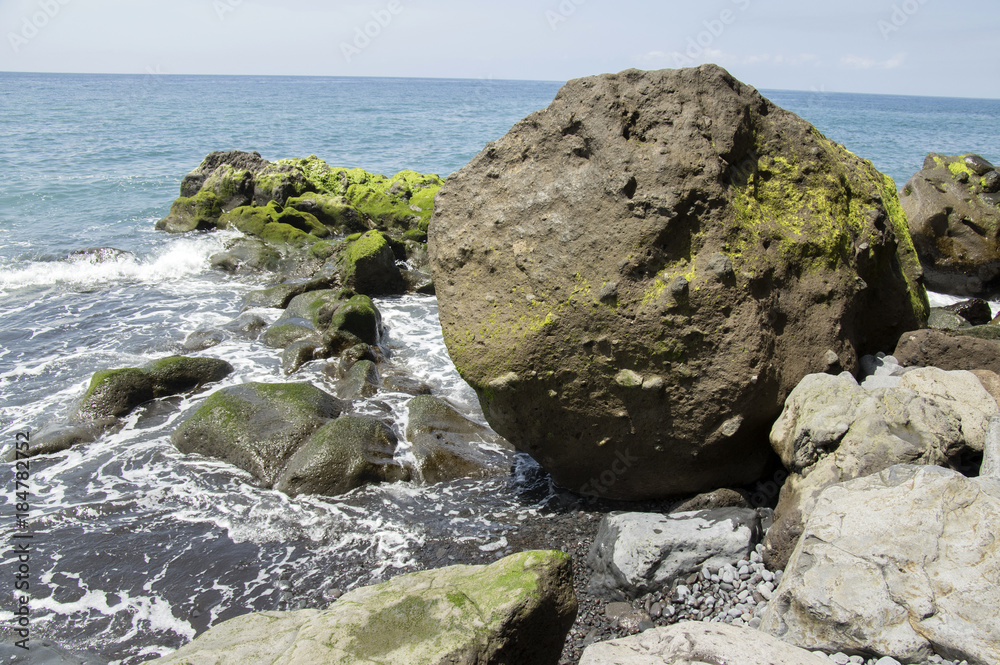 Beach Ponta de Sol rocky green coastline with cliffs and big volcano stones, Madeira island, Portugal Beach Ponta de Sol rocky green coastline with cliffs and big volcano stones, Madeira island, Portugal
