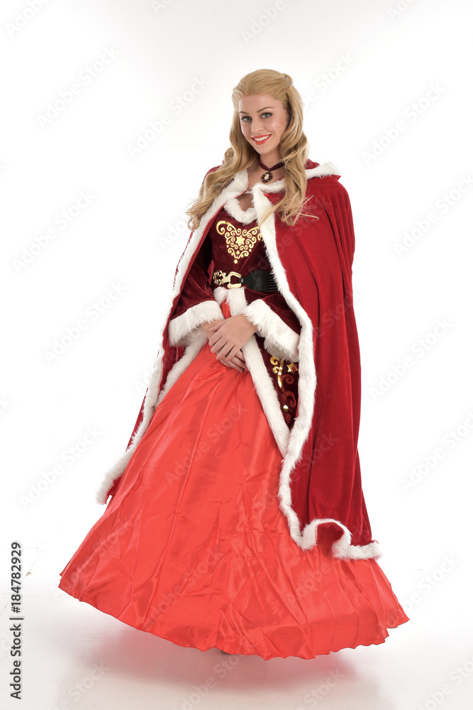 full length portrait of pretty blonde lady wearing red and white christmas inspired costume gown, standing pose on white background.