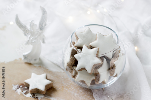 Cookies Cinnamon star in a glass vase on a white background decorated with a figurine of an angel and a garland. photo