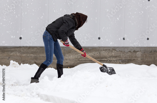 Girl with a shovel cleans the snow