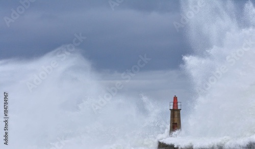 Stormy wave over old lighthouse and pier of Viavelez. © StockPhotoAstur