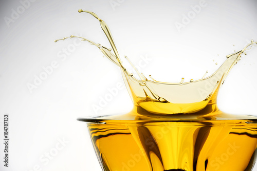 Side view of cooking oil splashing in container, studio background.