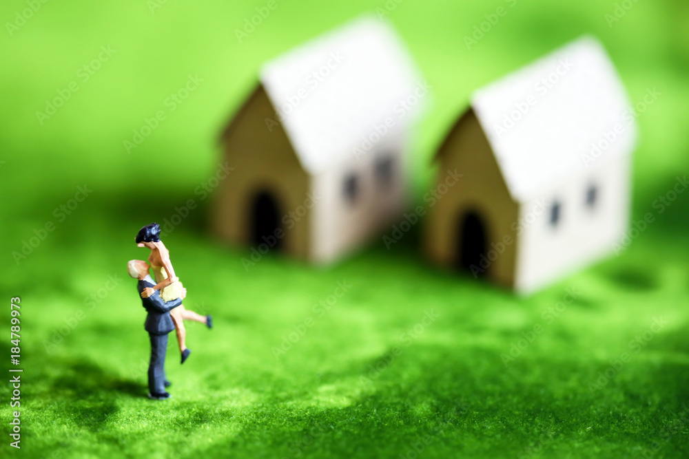 Miniature couple people hugging in garden over blur home and green background