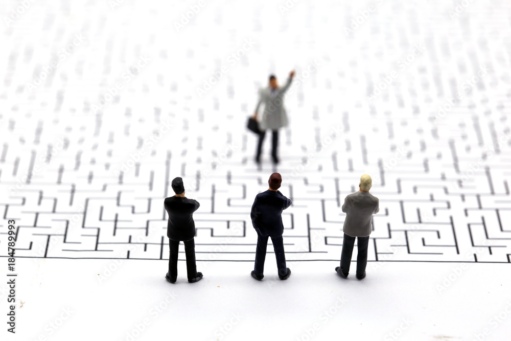 Miniature people: Businessman teams standing on center of maze Miniature people: Businessman teams standing on center of maze