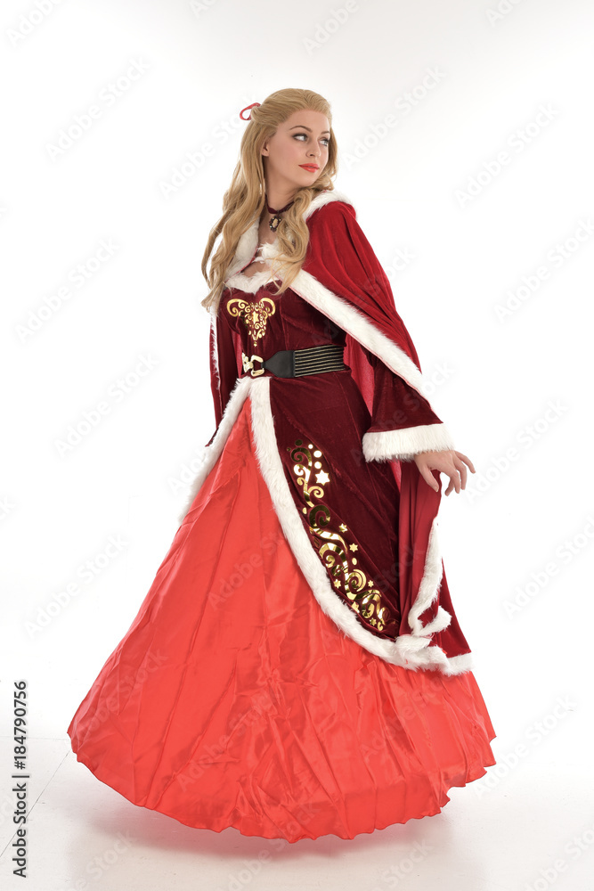 full length portrait of pretty blonde lady wearing red and white christmas inspired costume gown, standing pose on white background.