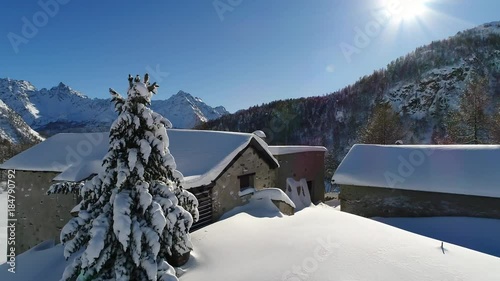 Little huts in mountain covered with snow. Flying with drone over the forest and beautiful chalets