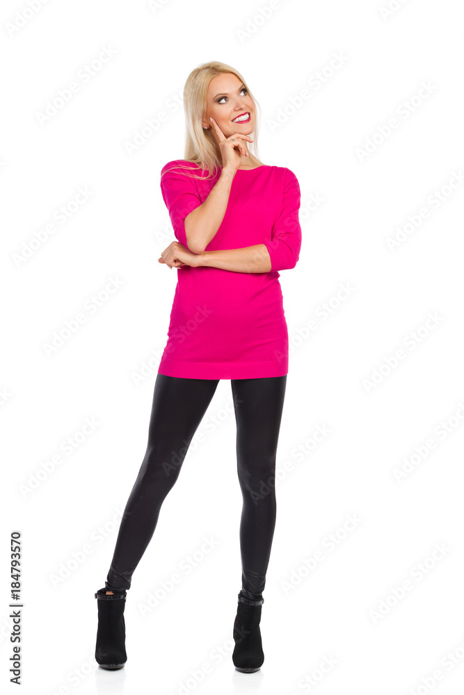 Smiling Beautiful Blond Woman Is Standing With Hand On Chin, Looking Away And Thinking Smiling Beautiful Blond Woman Is Standing With Hand On Chin, Looking Away And Thinking