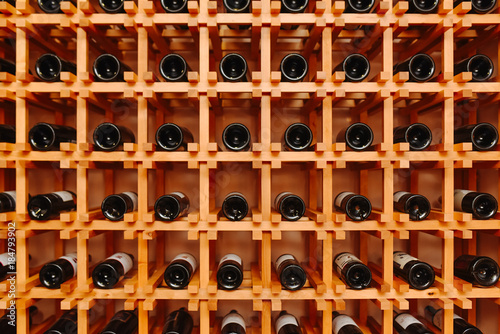 The bottles on the shelves of the wine cellar. Front view