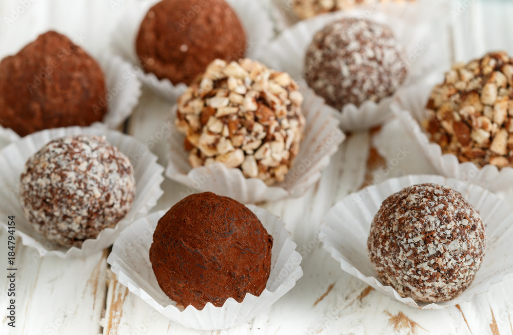 Assorted dark chocolate truffles with cocoa powder, coconut and chopped almonds closeup. Homemade candy. Selective focus Assorted dark chocolate truffles with cocoa powder, coconut and chopped almonds closeup. Homemade candy. Selective focus