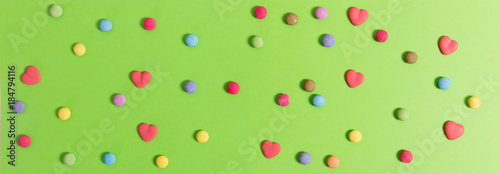 Colorful candies on green background, top view