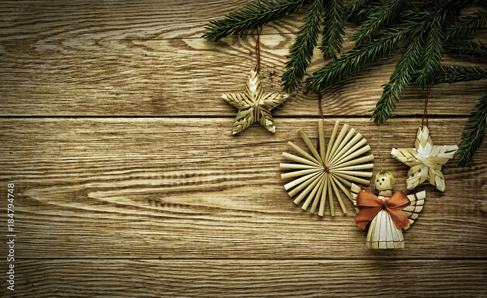 Christmas vintage wooden background with branches of fir tree and straw decorations