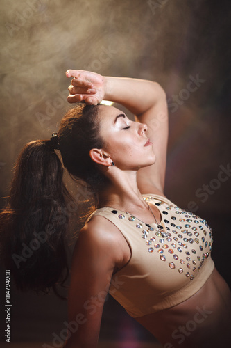 portrait of a sporty young woman with a tail in the top in the dark interior with lights and smoke.