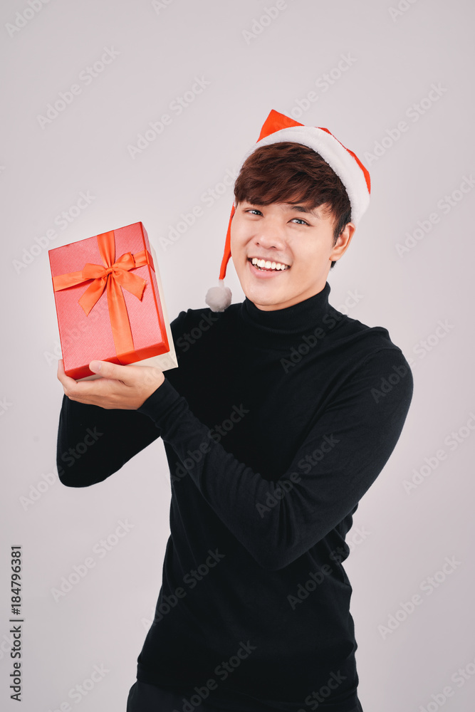 Young handsome asian man with santa hat holding a gift, isolated Young handsome asian man with santa hat holding a gift, isolated