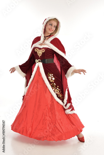 full length portrait of pretty blonde lady wearing red and white christmas inspired costume gown, standing pose on white background.