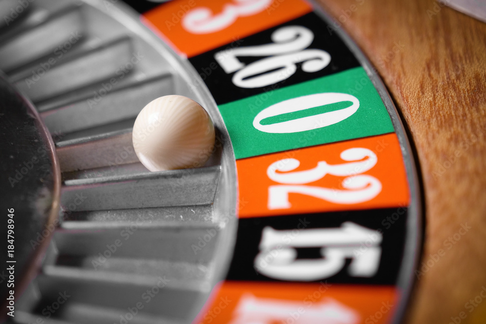 Macro shot of a roulette in a casino where the ball goes to the green or red or black number. People having bet and bet money may have won lost badges. Concept of: fate, gambling, luck, destiny. Macro shot of a roulette in a casino where the ball goes to the green or red or black number. People having bet and bet money may have won lost badges. Concept of: fate, gambling, luck, destiny.