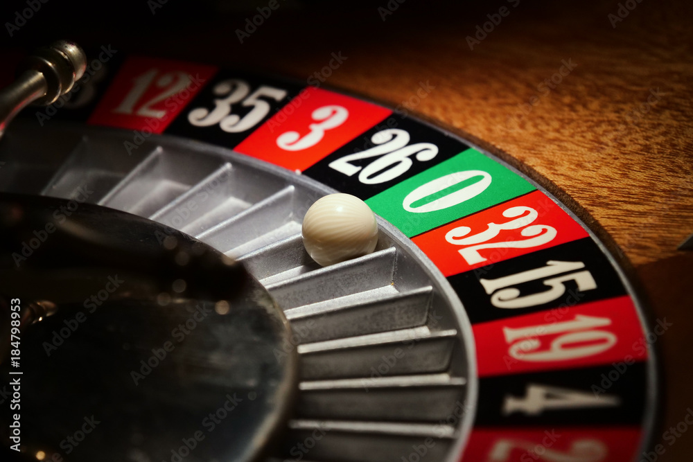 Macro shot of a roulette in a casino where the ball goes to the green or red or black number. People having bet and bet money may have won lost badges. Concept of: fate, gambling, luck, destiny. Macro shot of a roulette in a casino where the ball goes to the green or red or black number. People having bet and bet money may have won lost badges. Concept of: fate, gambling, luck, destiny.
