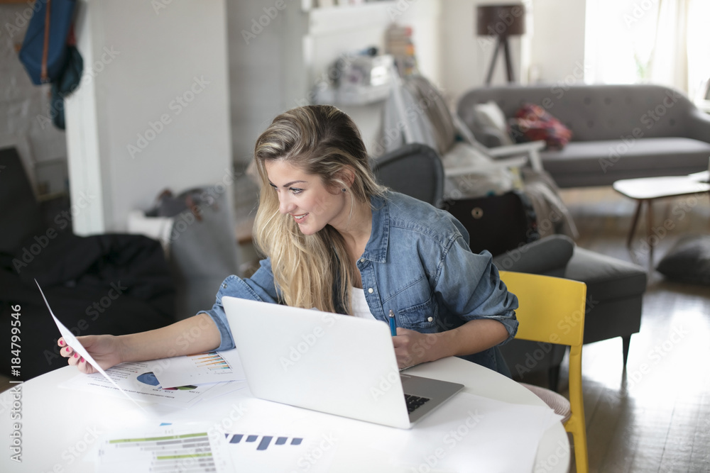 Obraz premium Young beautiful woman works for a computer from a home with a laptop on a white desk as a freelancer
