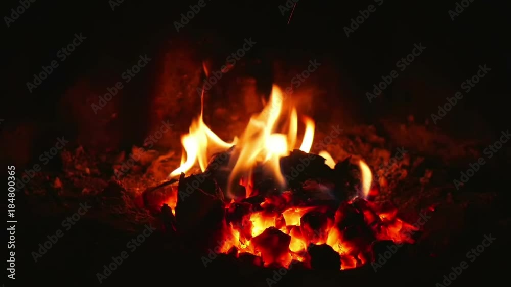 Orange flames from almost burned logs in open fireplace in super slow motion.