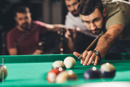 young handsome man playing in pool with friends at bar photo