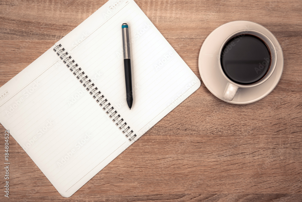A cup of coffee with note and pen on working table with copy space top view. A cup of coffee with note and pen on working table with copy space top view.