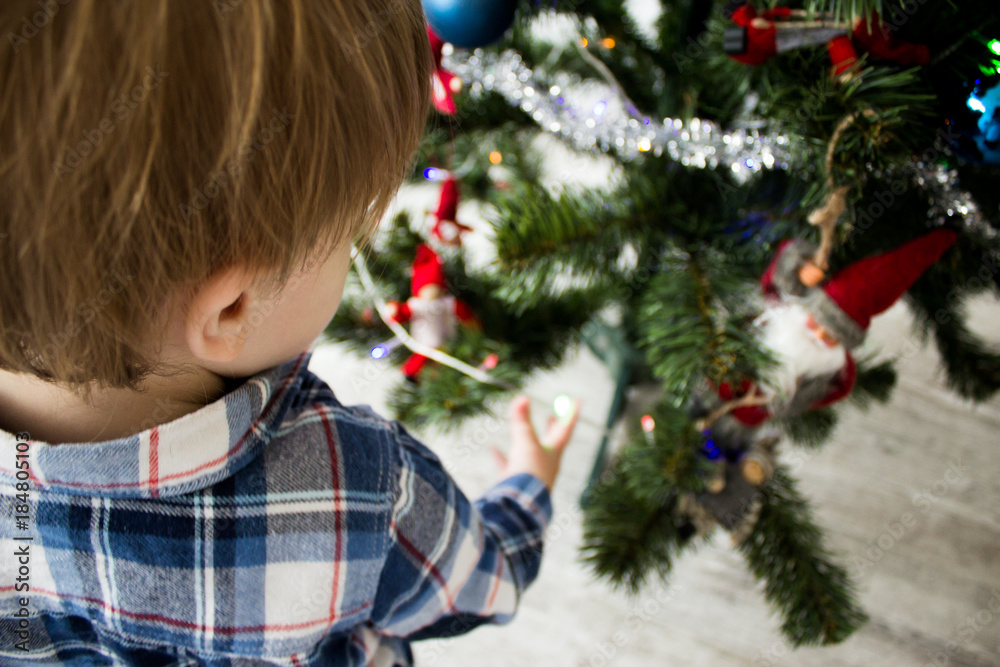 cute little boy playing near Christmas tree. beautiful and cute toddler boy sits near Christmas tree. holidays