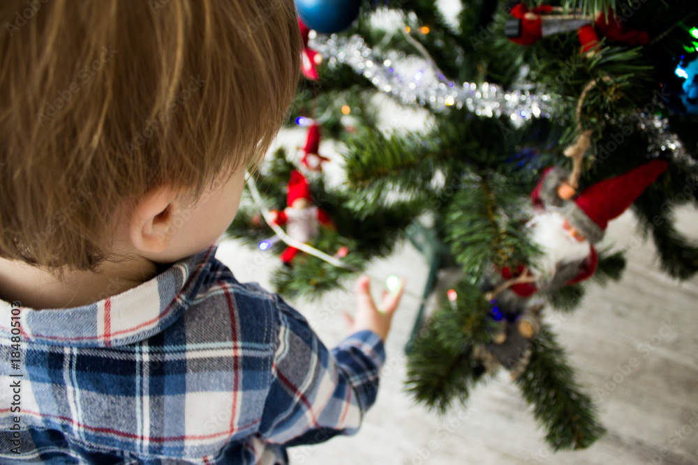 cute little boy playing near Christmas tree. beautiful and cute toddler boy sits near Christmas tree. holidays cute little boy playing near Christmas tree. beautiful and cute toddler boy sits near Christmas tree. holidays