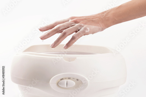 Woman in a nail salon receiving a manicure, she is bathing her hands in paraffin Fototapet