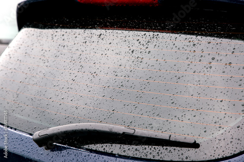 The rear window of the car with droplets.