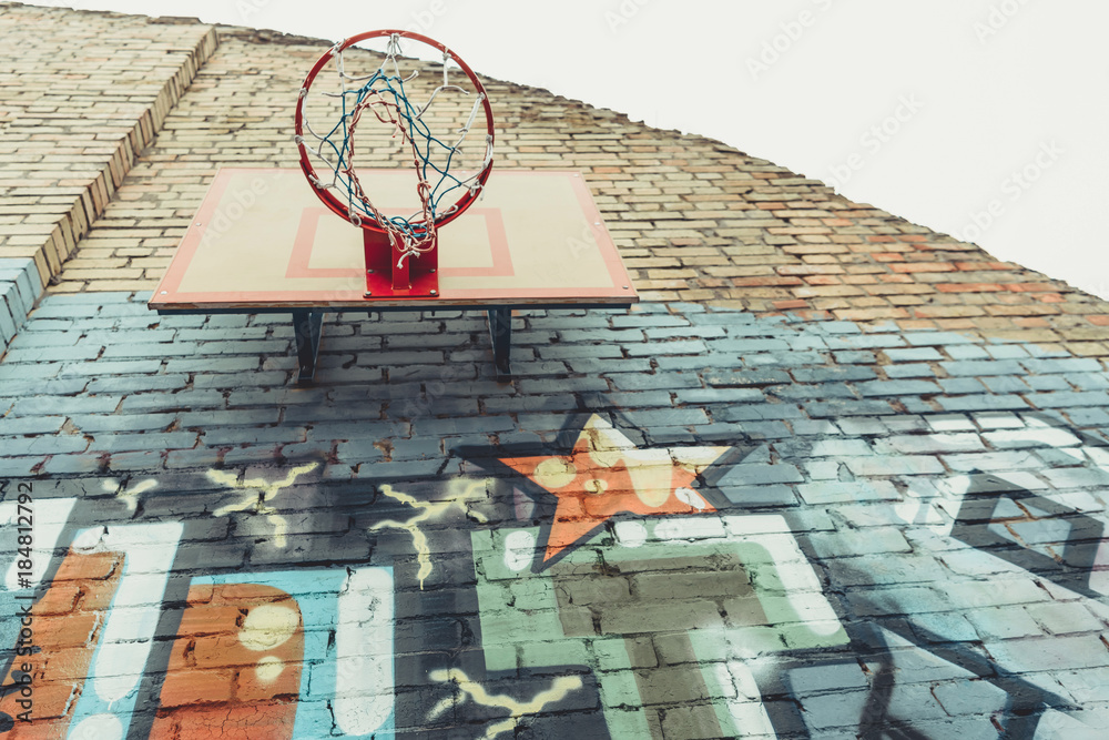bottom view of basketball hoop on wall with colorful graffiti