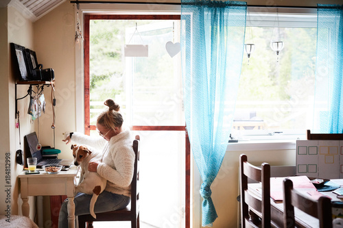 Side view of disabled woman with dog sitting on chair at home