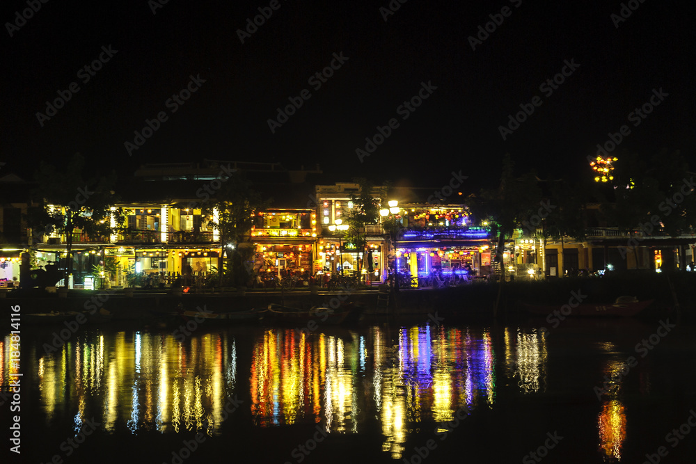 houses to the shore of the river Thu Bon illuminated in the night in Hoi An, Vietnam.