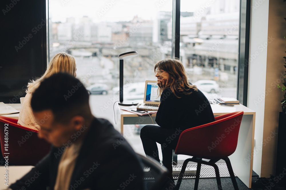 Young female colleagues sitting at desk in office Young female colleagues sitting at desk in office