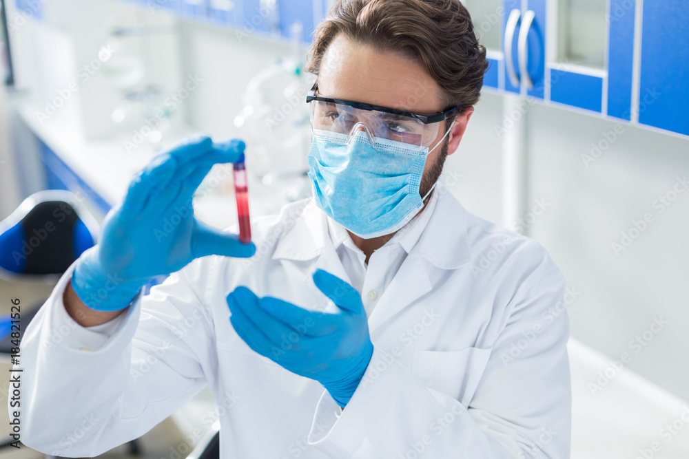 Nice professional doctor looking at the blood sample Nice professional doctor looking at the blood sample