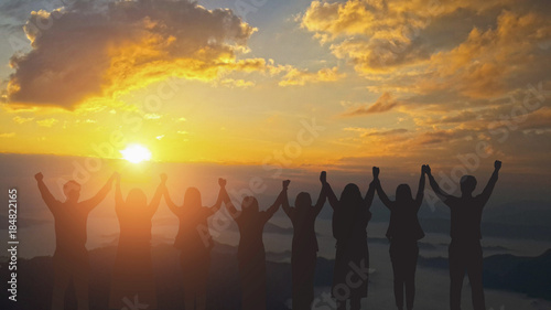 Silhouette image of happy teamwork join hands together up to the beautiful sky, successful business from good partnership and colleagues. photo