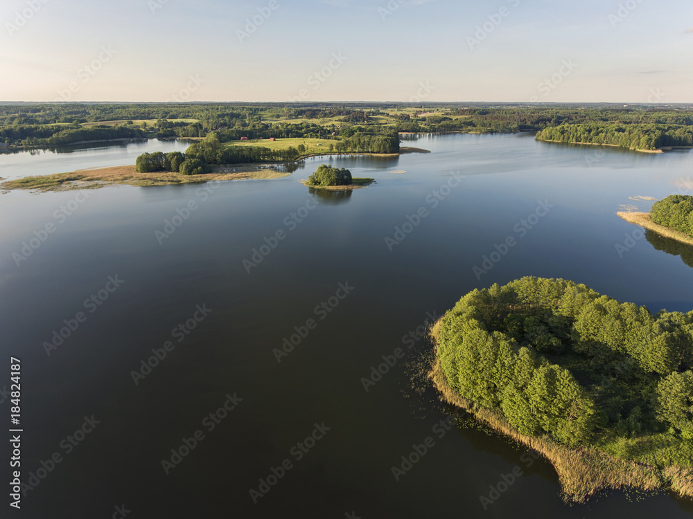 Aerial view over beautiful lake Uosis with a historical mound and small island in it near Veisiejai village, Lithuania. During sunny summer evening.