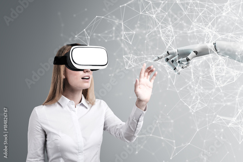 Woman in VR glasses, robot hand