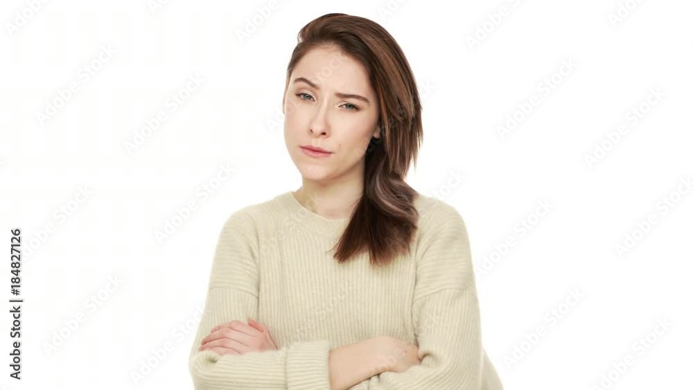 Portrait of serious young woman posing at camera with crossed arms feeling negative answering NO with shaking head expressing suspicion over white background closeup. Concept of emotions Portrait of serious young woman posing at camera with crossed arms feeling negative answering NO with shaking head expressing suspicion over white background closeup. Concept of emotions
