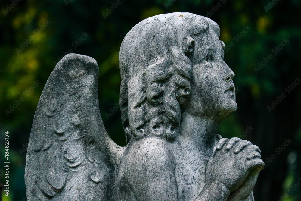 Mystic old statue of the praying angel. Sad sculpture of the angel pray the god.