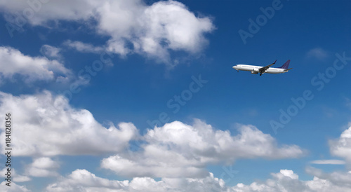 Commercial passenger airplane landing or taking off from the airport with blue cloudy sky in the background