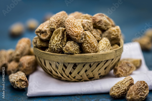 Close up of raw dried dates,Phoenix dactylifera in a traditional bowl on a wooden surface. photo