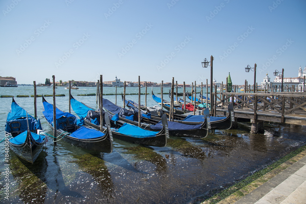 Gondolas moored by Saint Mark square with San Giorgio di Maggiore church in Venice, Italy - June 20, 2017