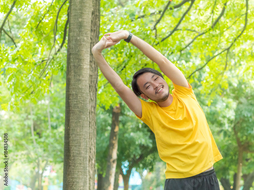 Young Asian man warm up his body before run in outdoor park