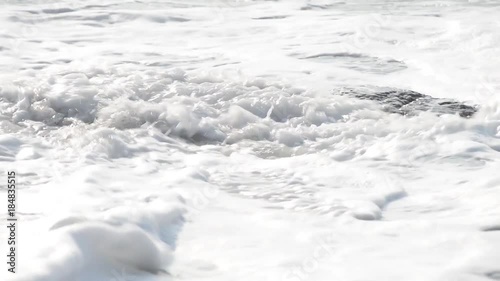 un sasso sulla battigia investito dalla schiuma dell'onda photo