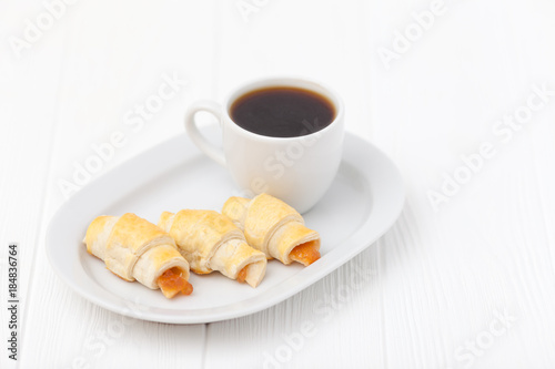 Freshly baked croissant  jam  cup of black coffee on white wooden background. Homemade cookie. Fresh pastries for breakfast. Delicious dessert. Closeup photography. Horizontal banner