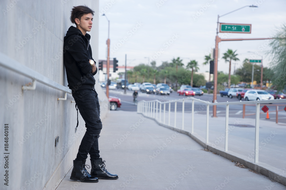 Young man leaning against wall on urban city street