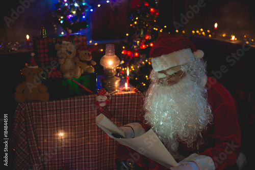 Santa claus read a paper at night in the house The light from the book Using the light from the lantern room